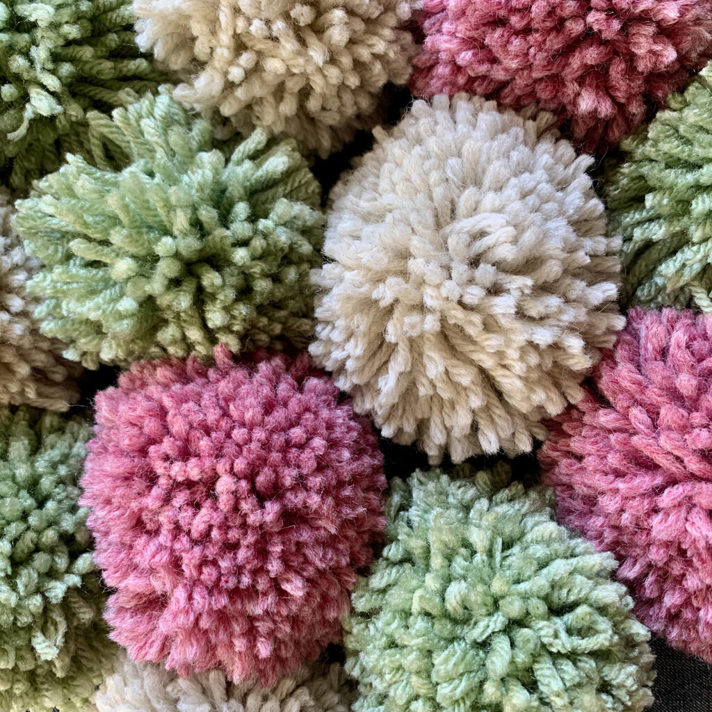 pile of white, pink, green, and beige pom poms