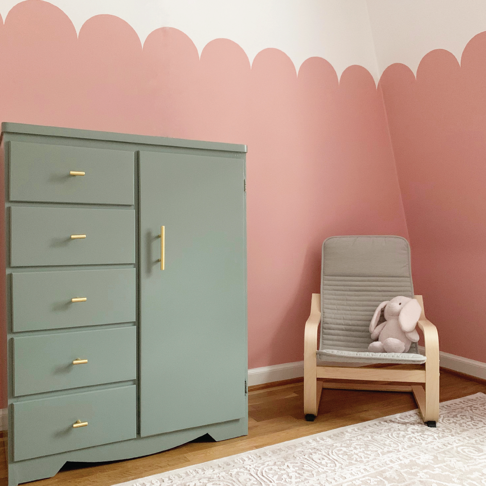 final scalloped walls with child's chair with pink bunny on it, and green wardrobe.