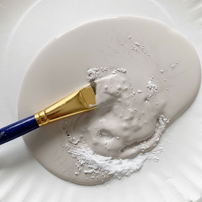 mixing beige paint and baking soda with a paint brush