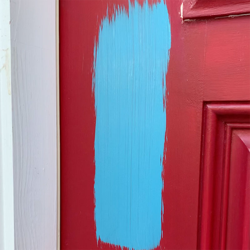 swatch of new blue paint painted on red door