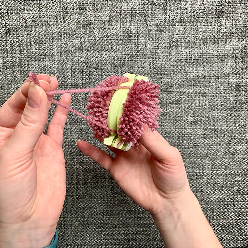 pull string through the middle of the Pom Pom maker