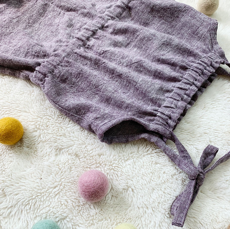 summer romper for kids by purl soho laying on blanket