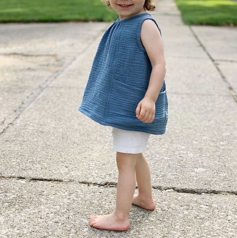 side view of two year old girl wearing sewn Wiksten smock top
