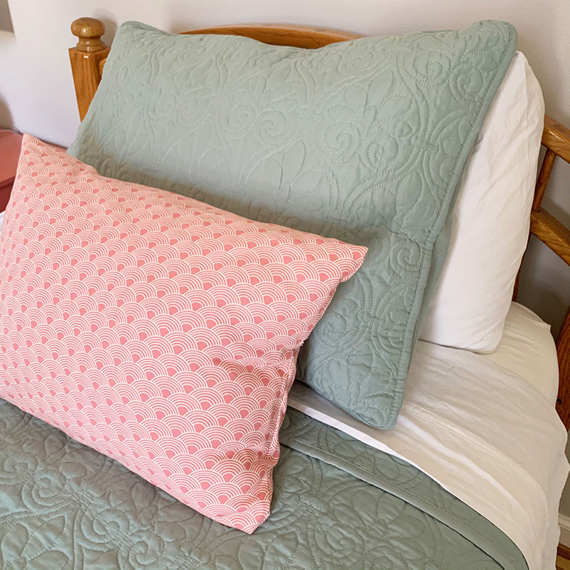 light green quilt and sham on bed with pink accent pillow
