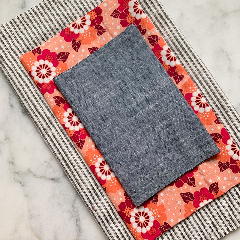 striped, floral, and chambray fabric laying on top of one another